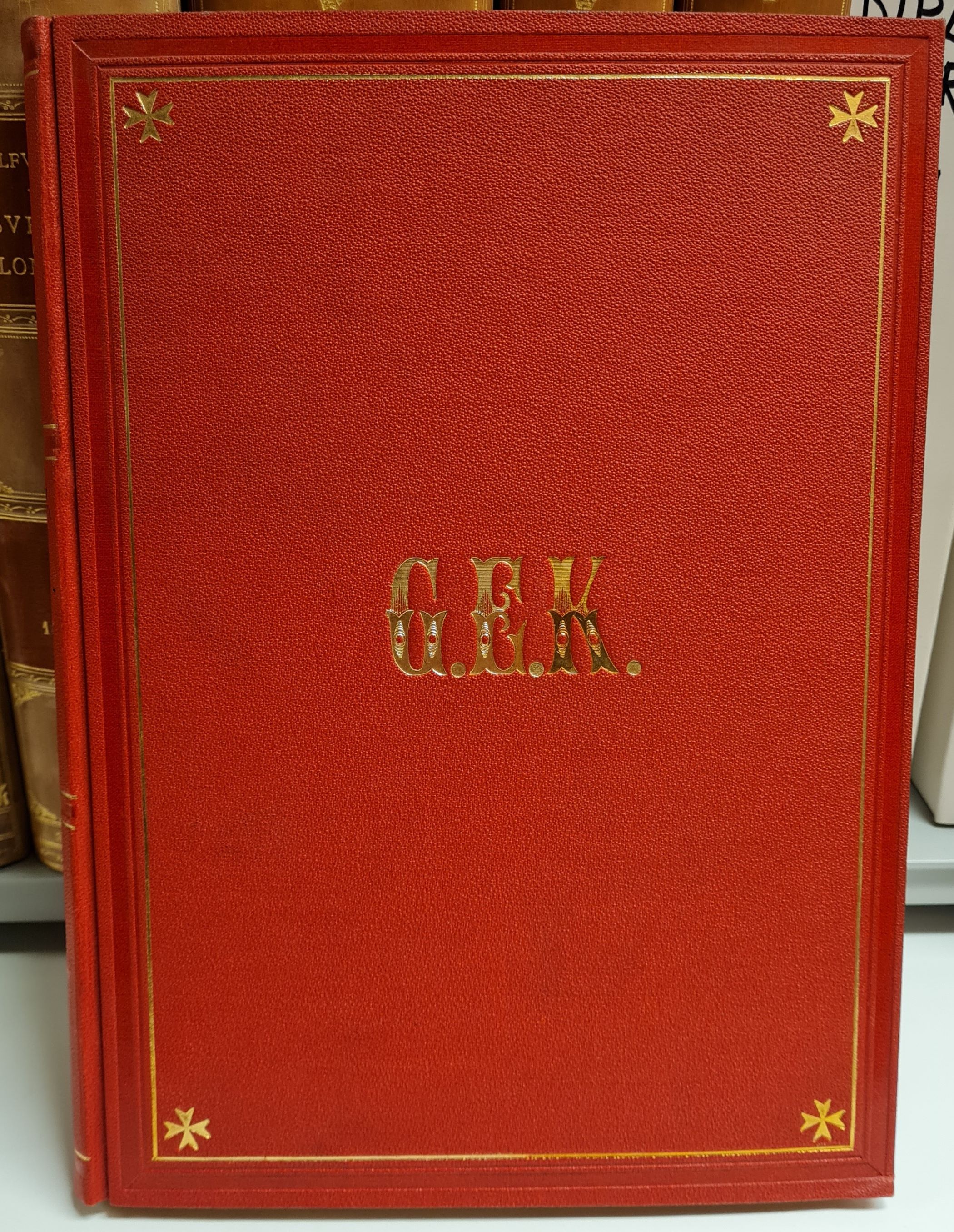 Färgfotografi av frampärmen på ett rött bokband med förgyllda detaljer, däribland fyra frimurarstjärnor och monogrammet G. E. K.