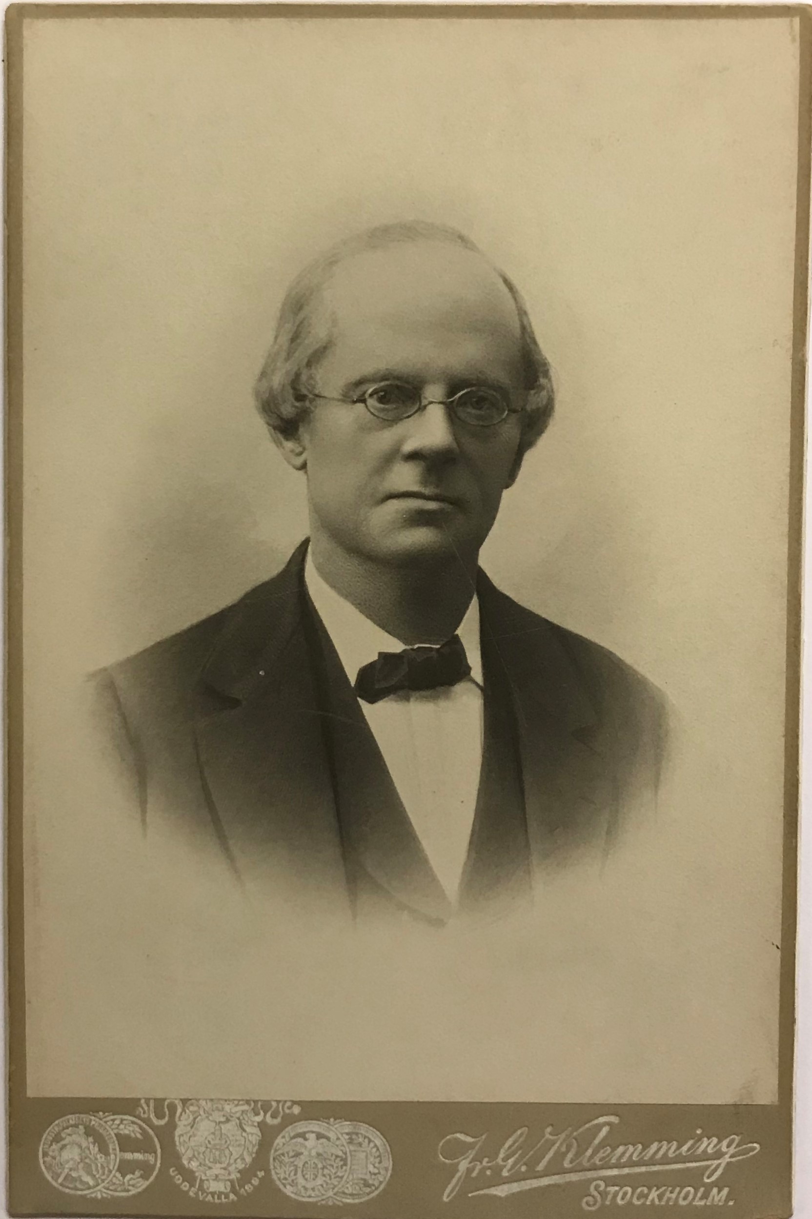Fotografi av en allvarlig man med hög panna och runda små glasögon.