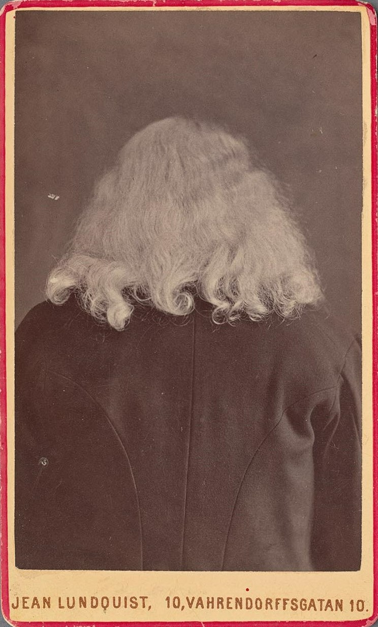 Svartvitt fotografi av ett vitt hårsvall över en svart ryggtavla.