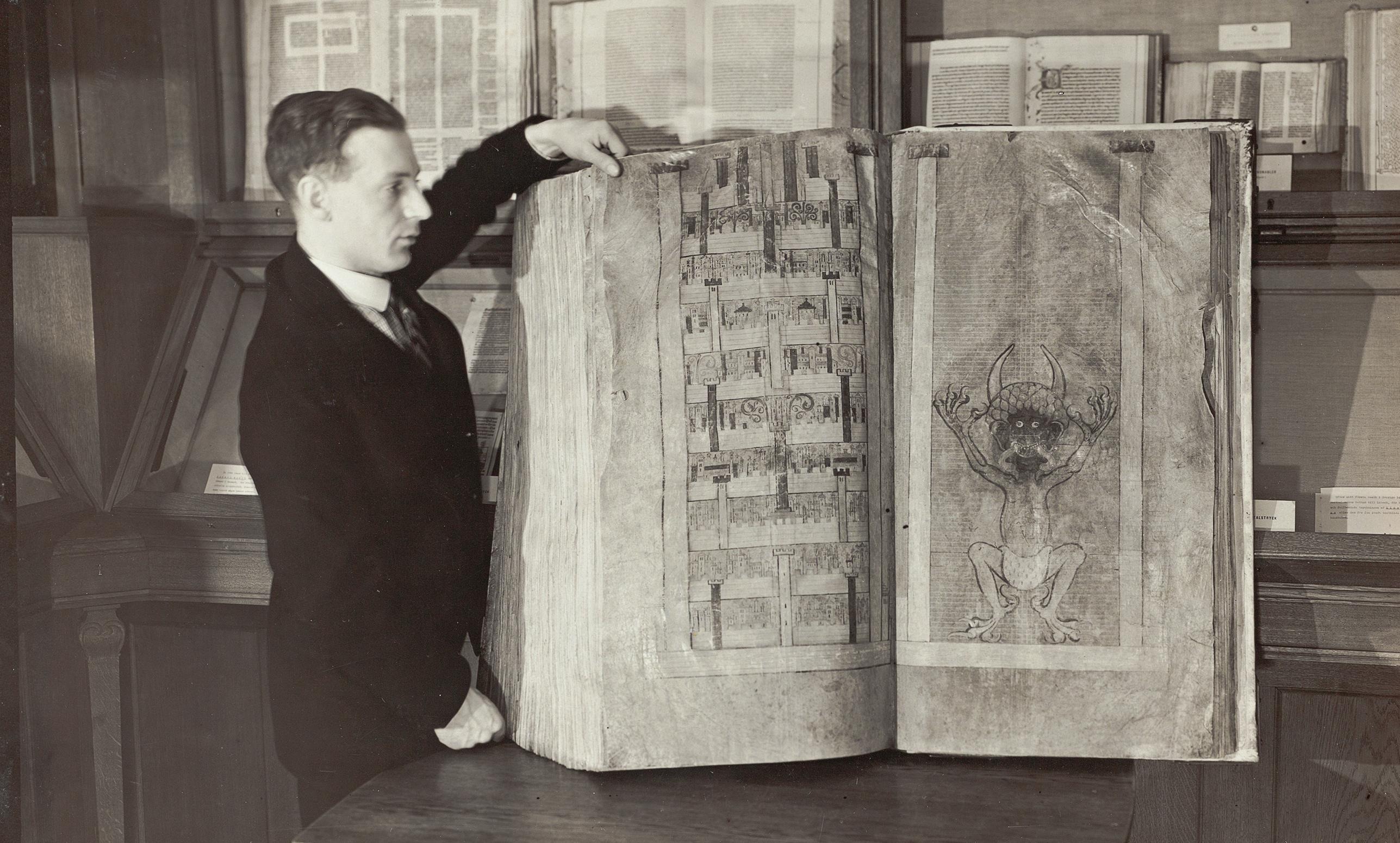 A black and white photo of a man showing a giant book.