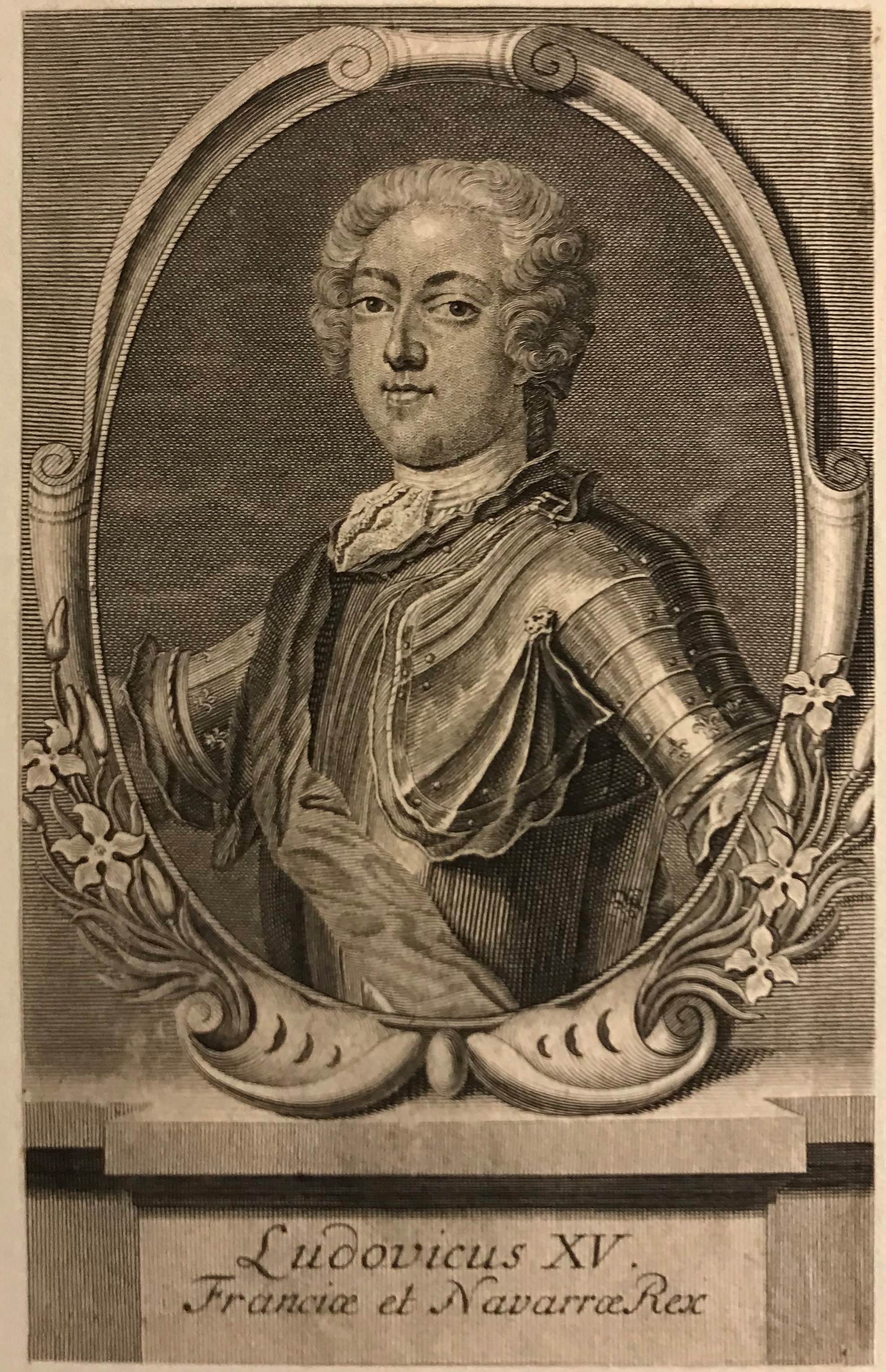 Gravyr föreställande en ung man med peruk, spetskrage och rustning i en oval ram. Under bilden texten "Ludovicus XV. Franciae et Navarrae Rex".