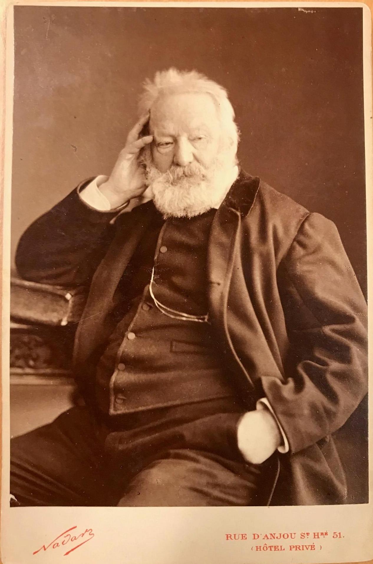 Porträtt av Victor Hugo sittande vid ett bord.