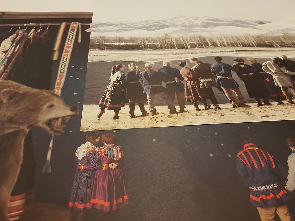 Två tryckta färgbilder. På den ena står en grupp samer på en rad framför ett fjällandskap, på den andra står samer i traditionella kläder framför en stjärnhimmel med en isbjörn till vänster.