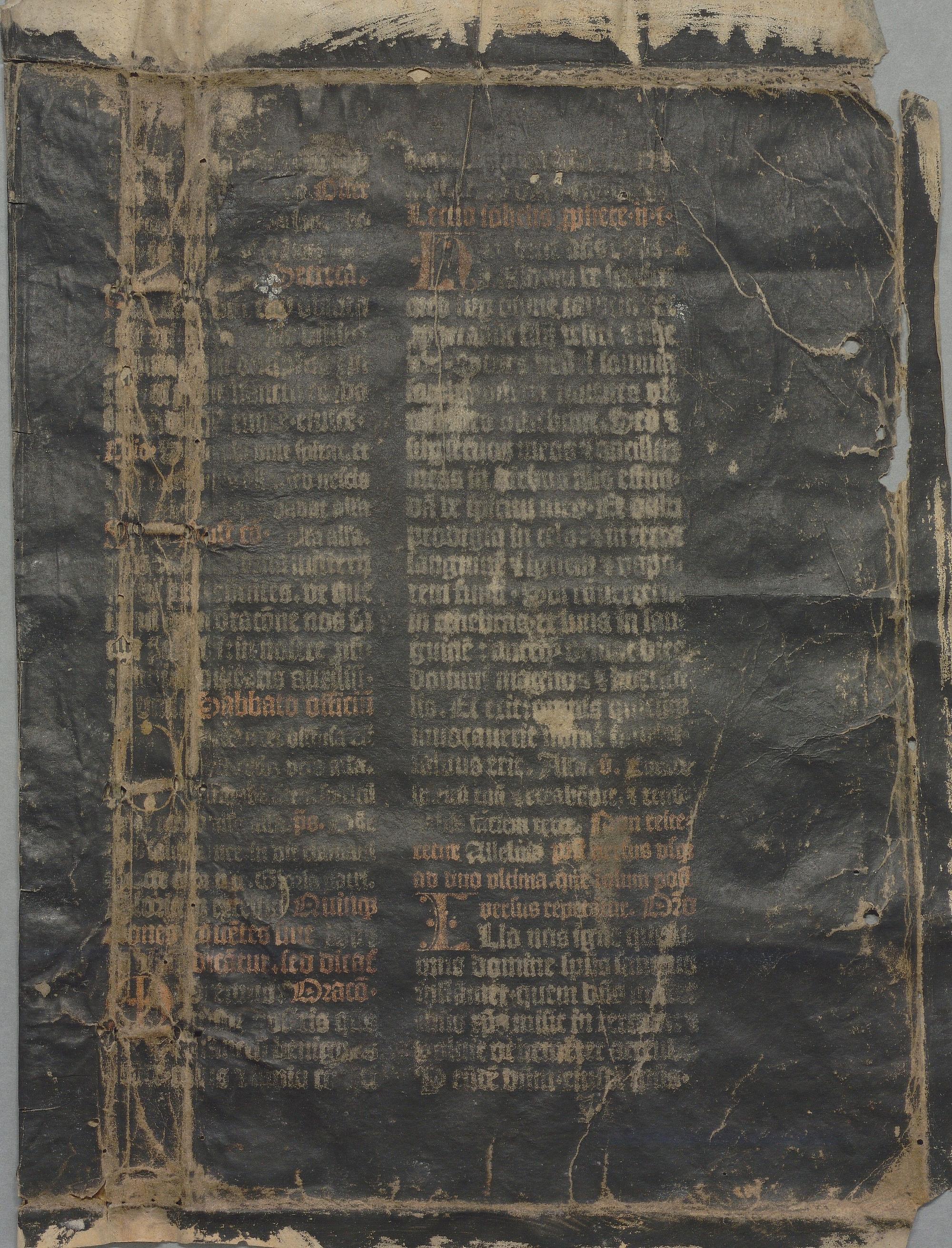 Färgfoto av en ett slitet ark med handskriven text i två spalter som målats över med svart färg.