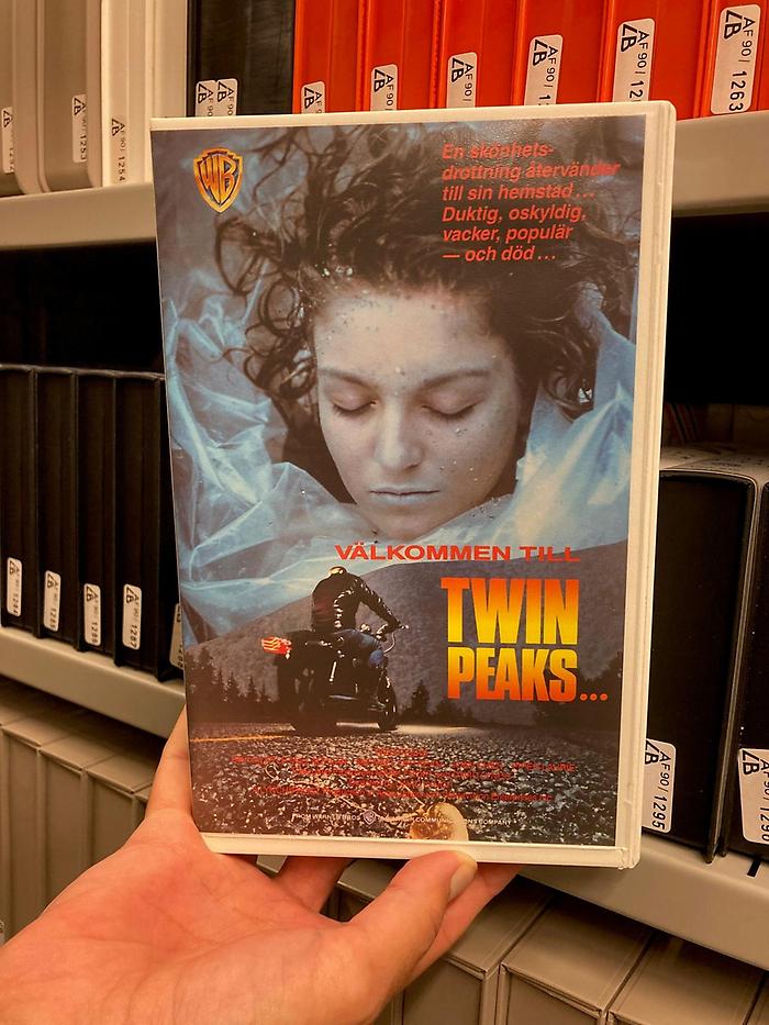 Hand som håller upp videoomslaget till filmen "Välkommen till Twin Peaks".