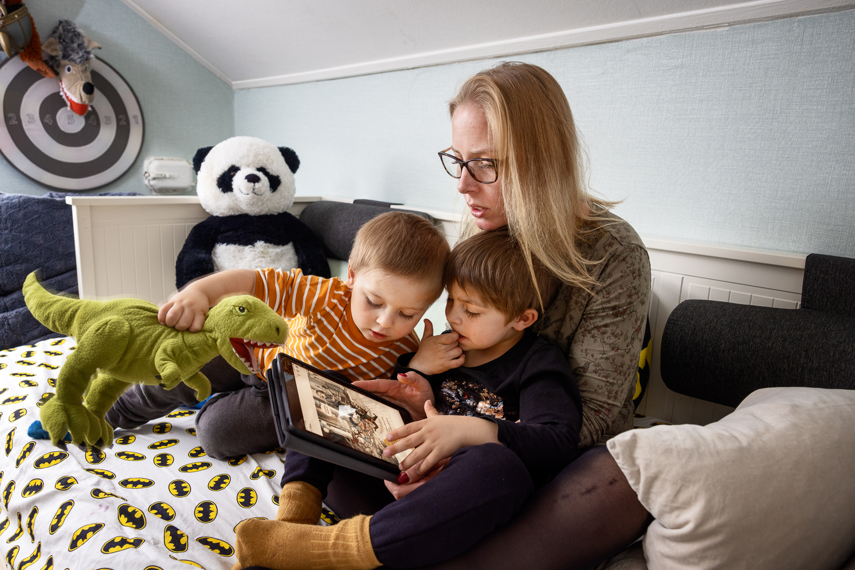 Användare av KB:s läsapp Bläddra: En kvinna sitter med två barn och läser ur appen Bläddra,med e-böcker på de nationella minoritetsspråken.