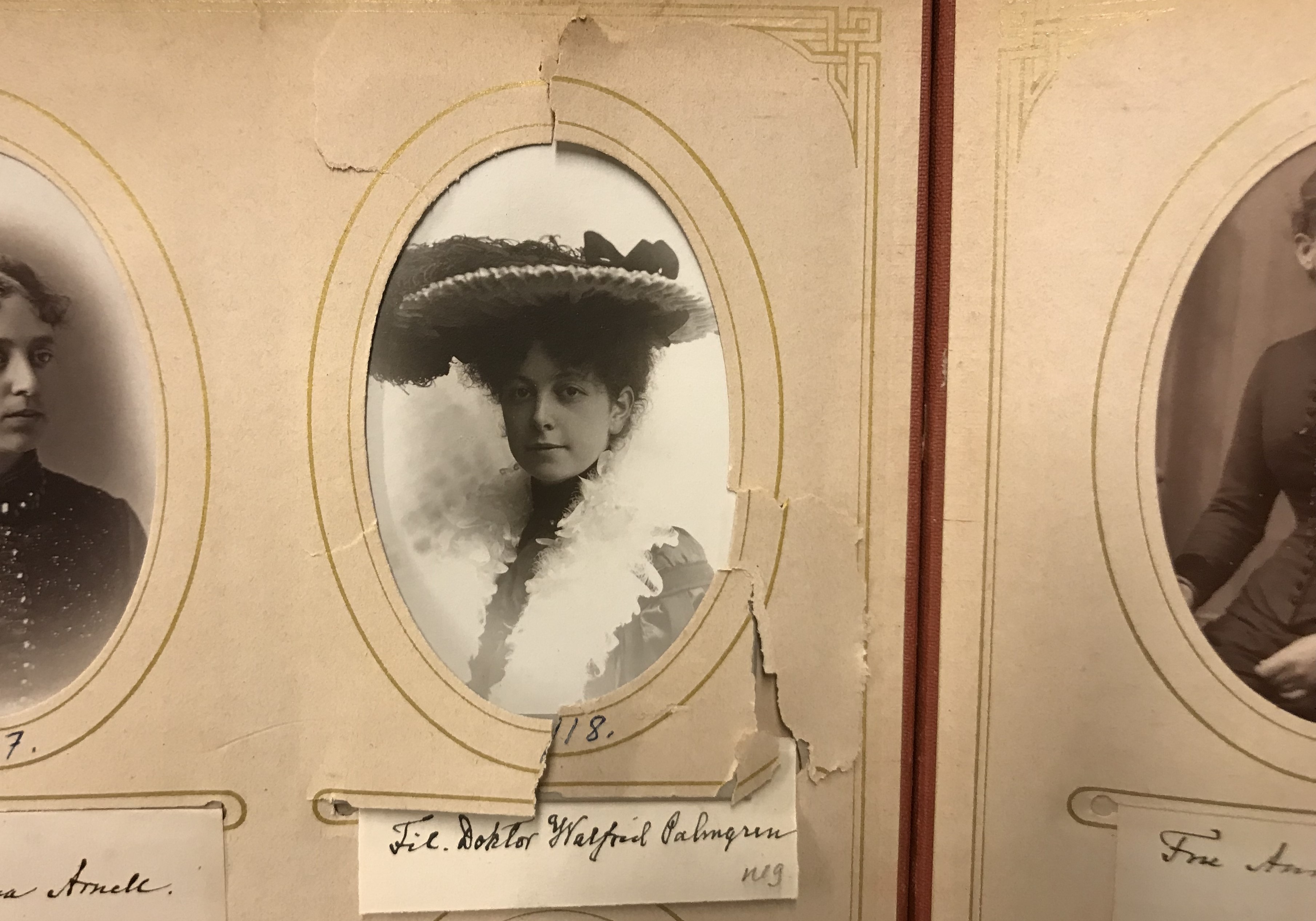 Del av ett något slitet fotoalbum med ett svartvitt fotografi av en yngre kvinna med bred hatt