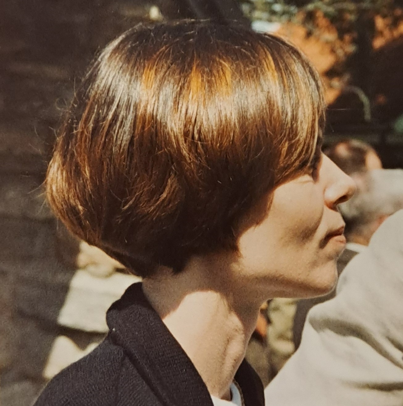 Färgfotografi av en ung kvinna med page-frisyr i profil.