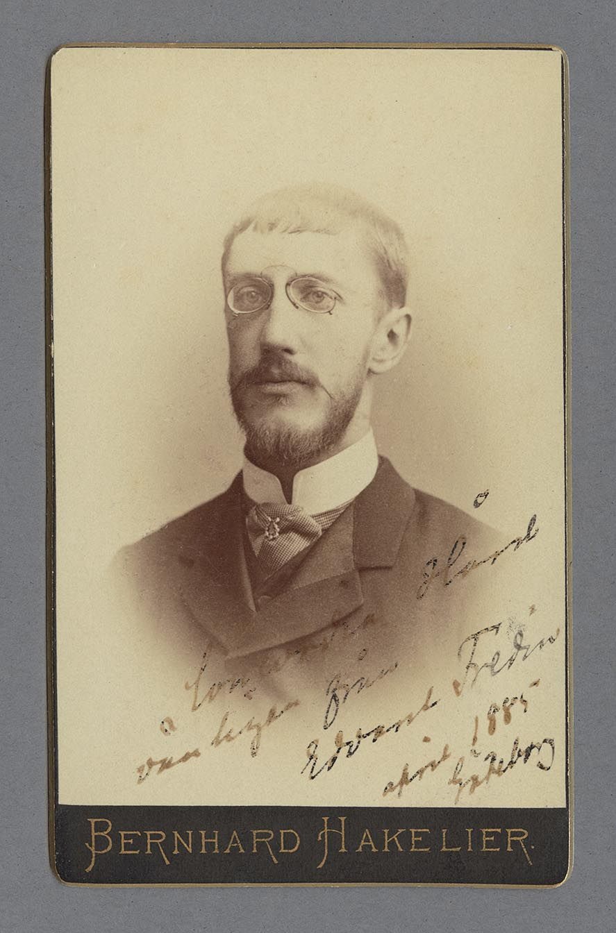Bystporträtt av Nils Edvard Fredin iklädd kavaj med höghalsad kravatt samt glasögon.
