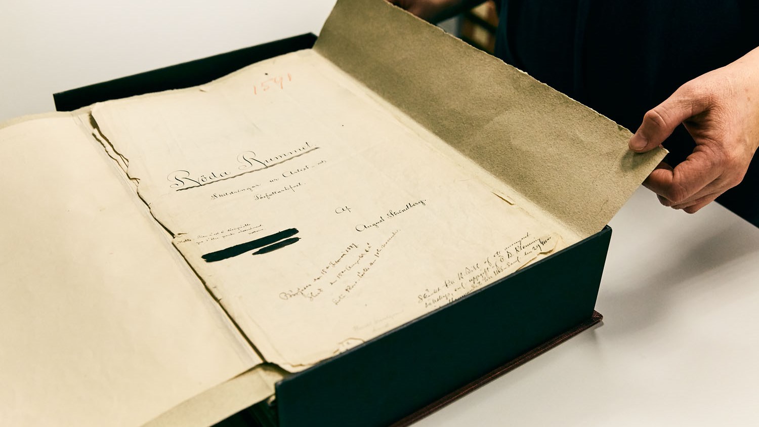 A person holding a manuscript by August Strindberg.