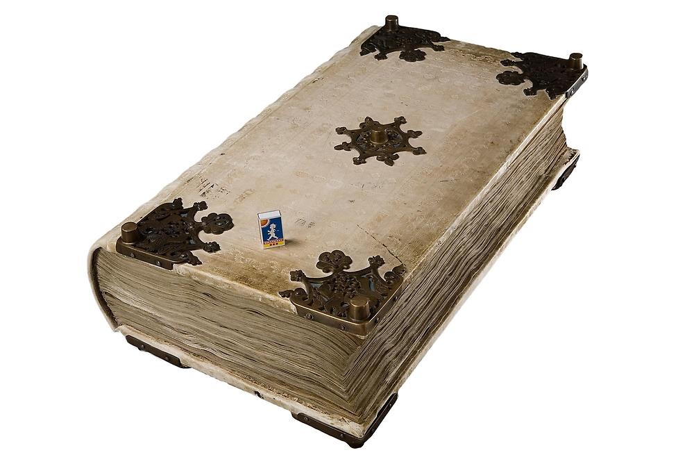 A huge white leather book with a small matchbox on top.