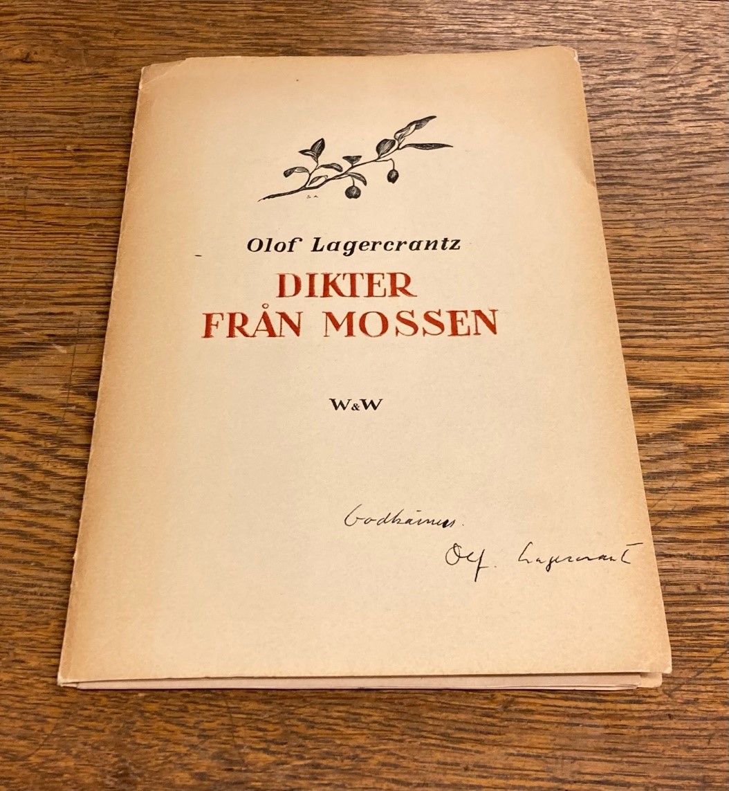 Färgfotografi föreställande en tunn tryckt volym med titeln Dikter från mossen i röda versaler, under titeln en handskriven text i svart bläck: Godkännes. Olof Lagercrantz