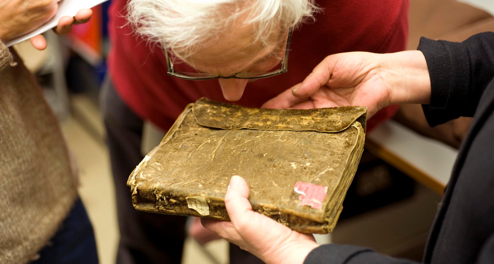 Äldre person lutar sig över en gammal bok som för att lukta på den.