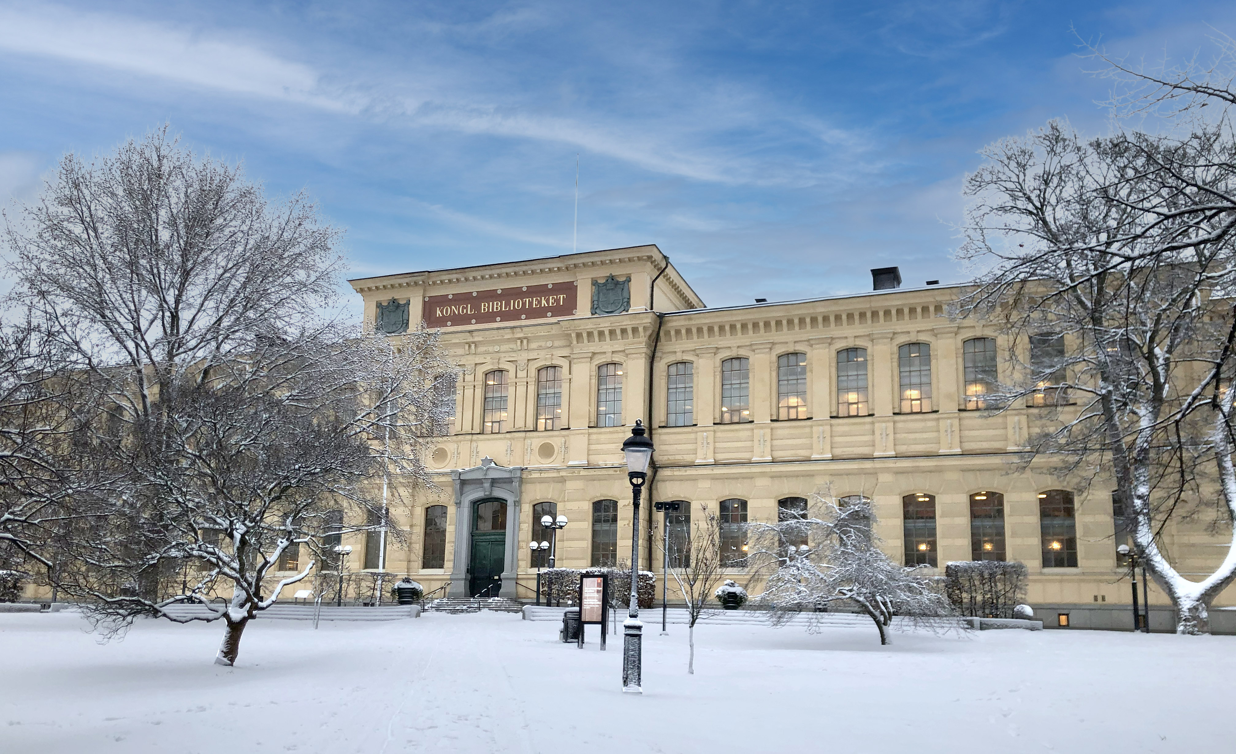 Kungliga bibliotekets gula tegelbyggnad i en snöklädd park.