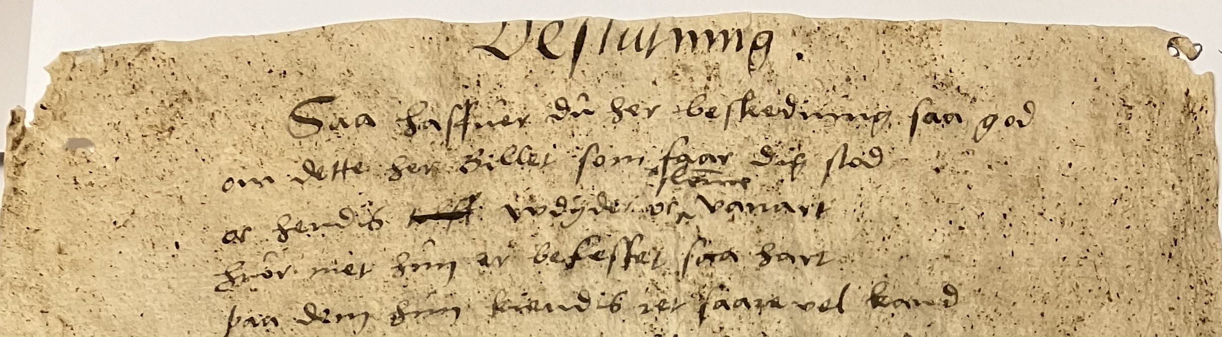 Närbild av handskriven text på ett gulnat och slitet pappersark, där ordet Beslutning står överst på sidan.