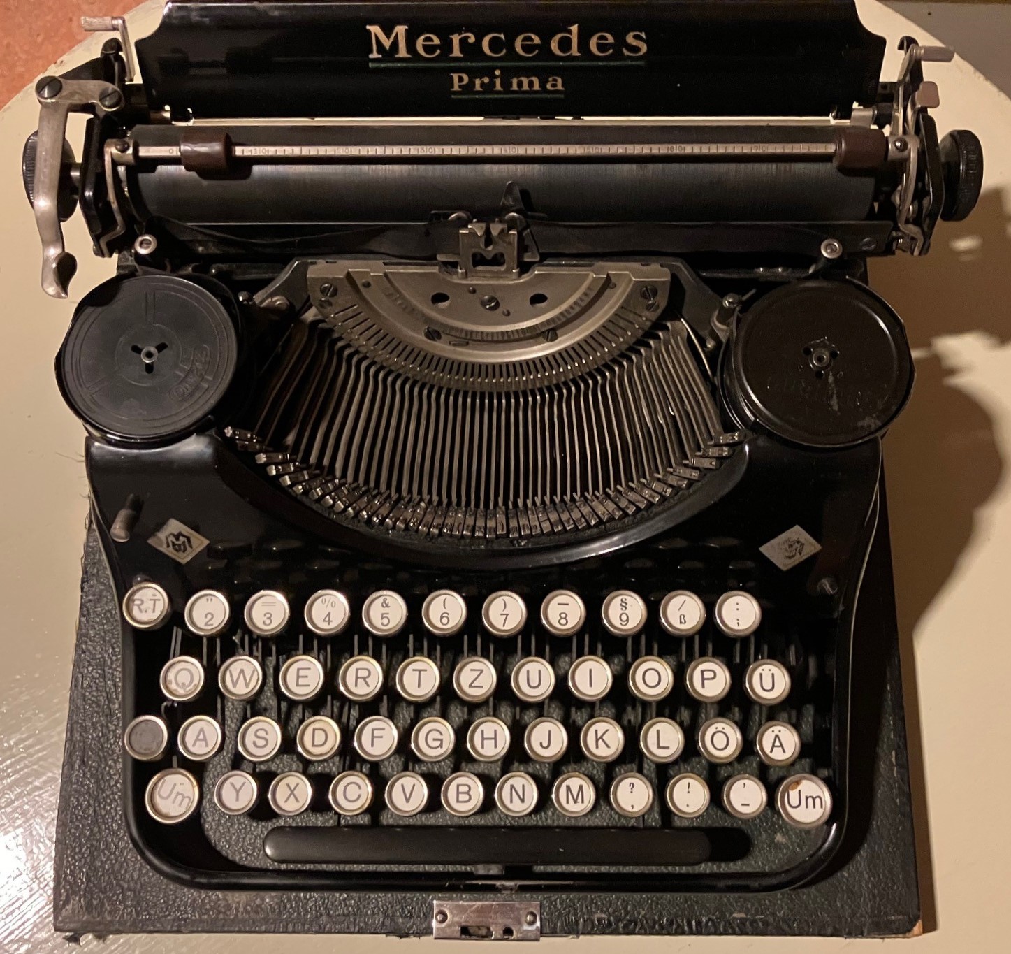 Färgfoto av äldre, svart skrivmaskin. Ovanför valsen står märket Mercedes Prima i guldbokstäver.