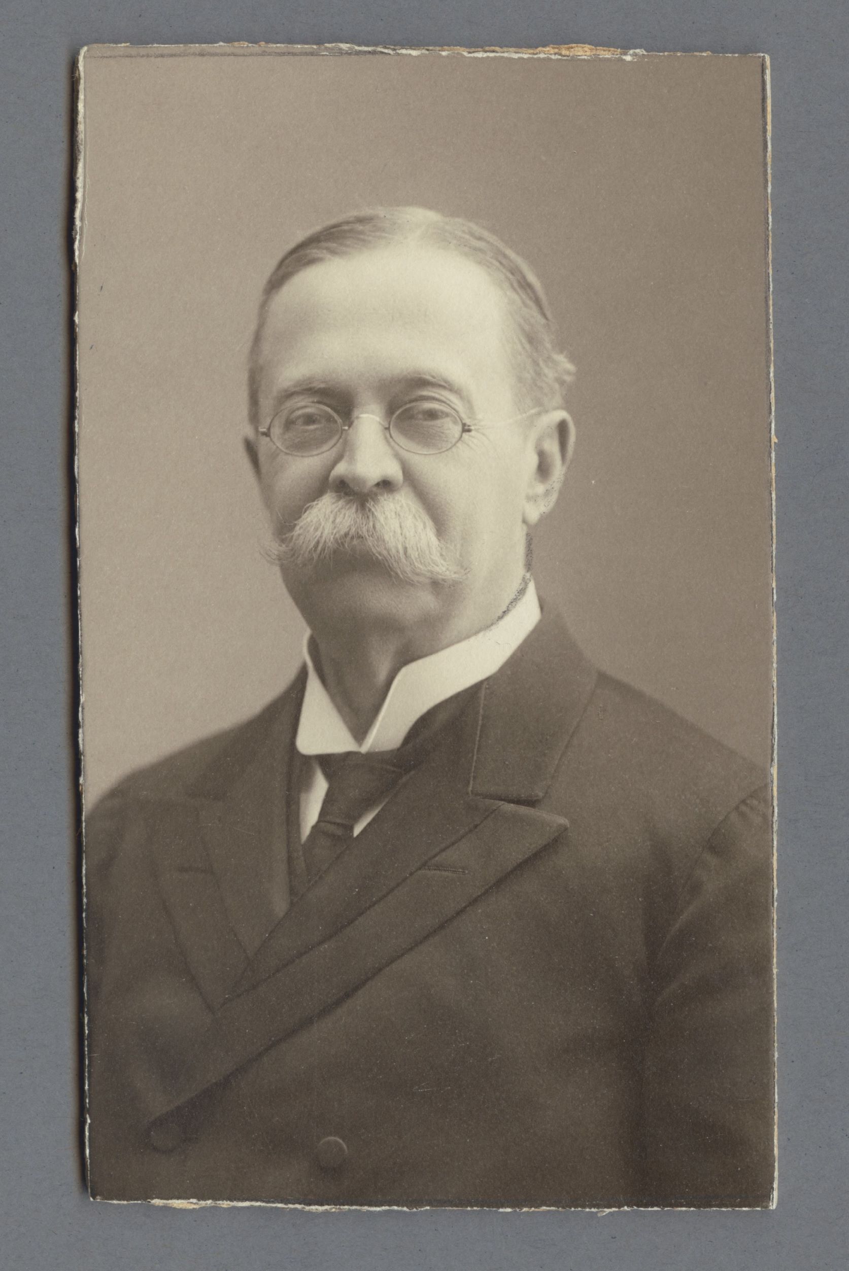 Bystporträtt av Ernst Geijer iklädd kavaj och slips samt glasögon.