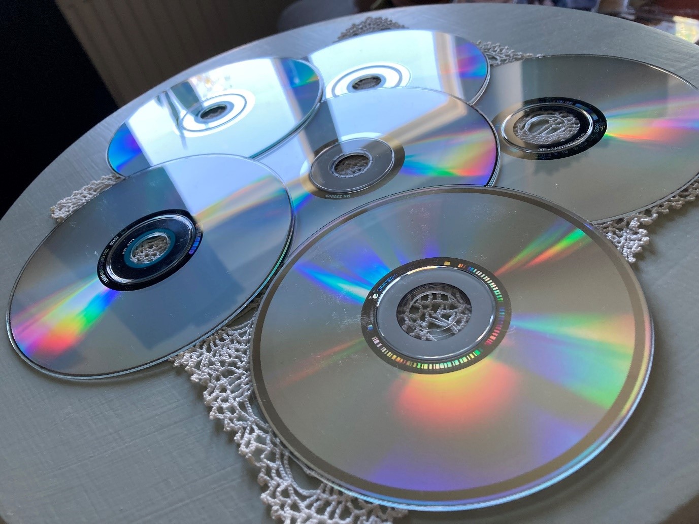 Fem cd-skivor ligger omlott på en virkad duk på ett bord
