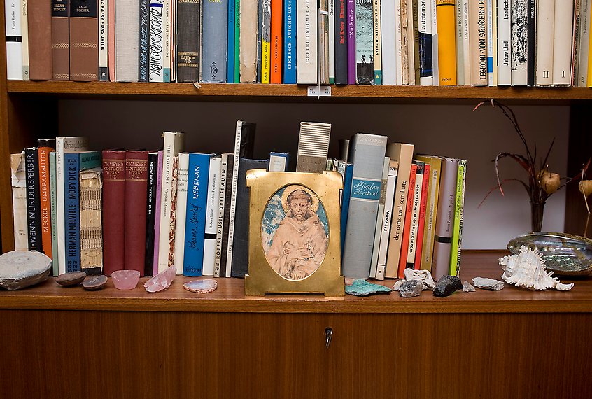 En bokhylla med prydnader och en ikontavla. 