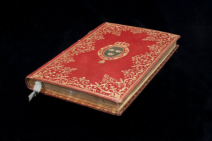 Äldre röd bok med guldornamentik.