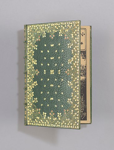 Äldre bok i grönt läderband med guldornamentik. 