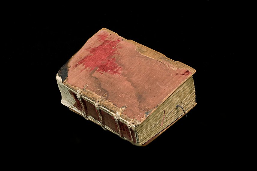 En äldre bok med rött slitet omslag.