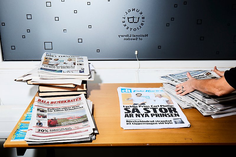 Tidningar på bord som hanteras av en person.