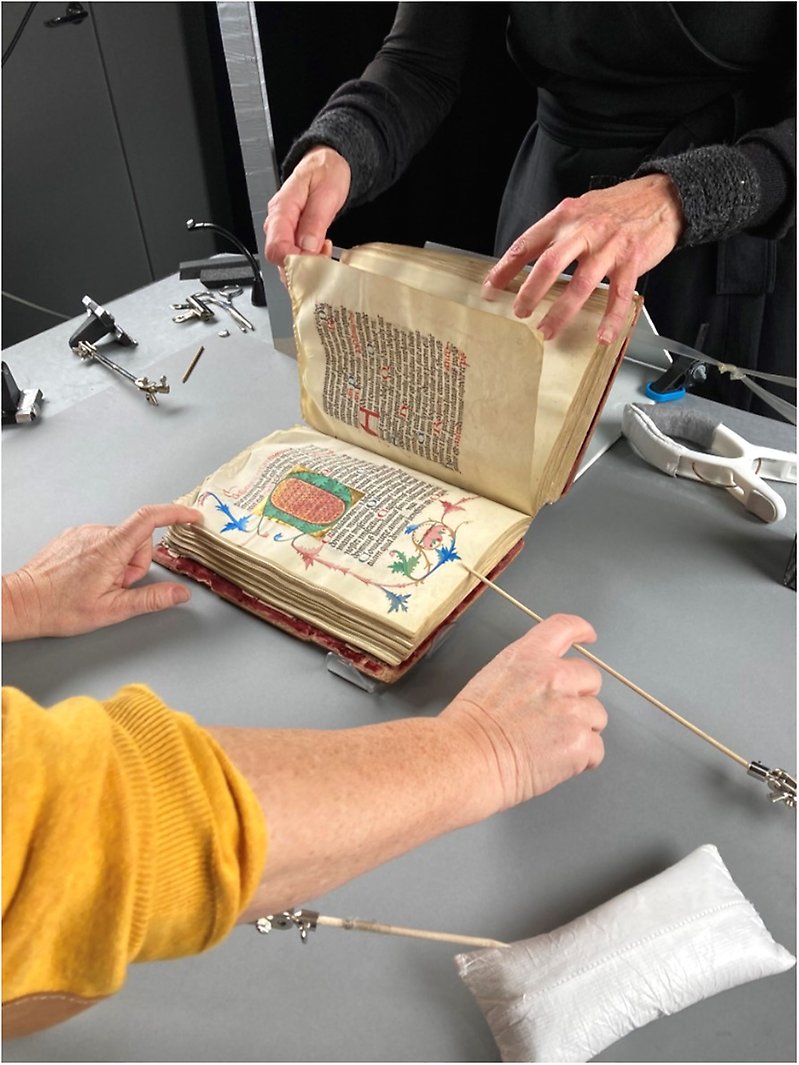 Two people carefully handle an old book.