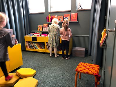 Barn som står och letar böcker i boklådor.